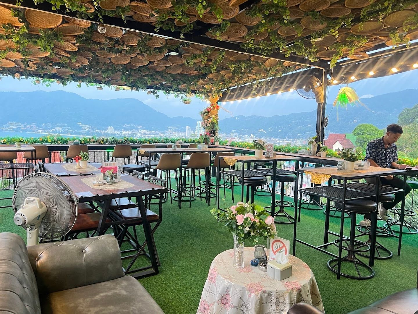 Jinny's authentic hillside terrace with seating, hanging greenery and views across Patong Bay